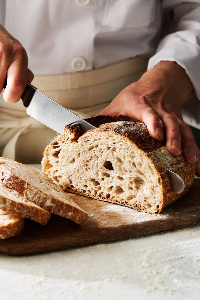 a person cutting a piece of bread