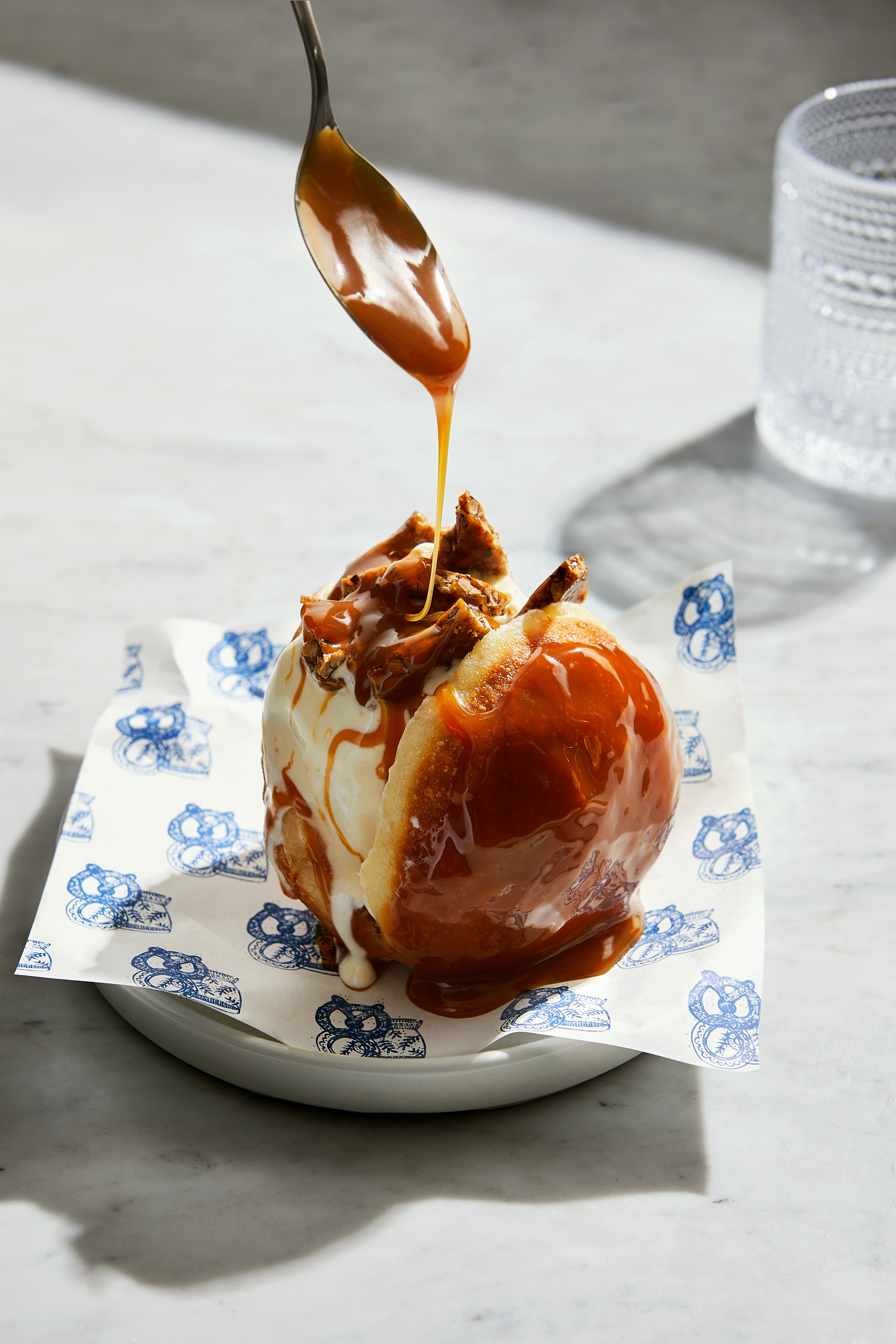 A spoon dips into rich caramel sauce, poised above a fresh apple, ready to create a delicious treat