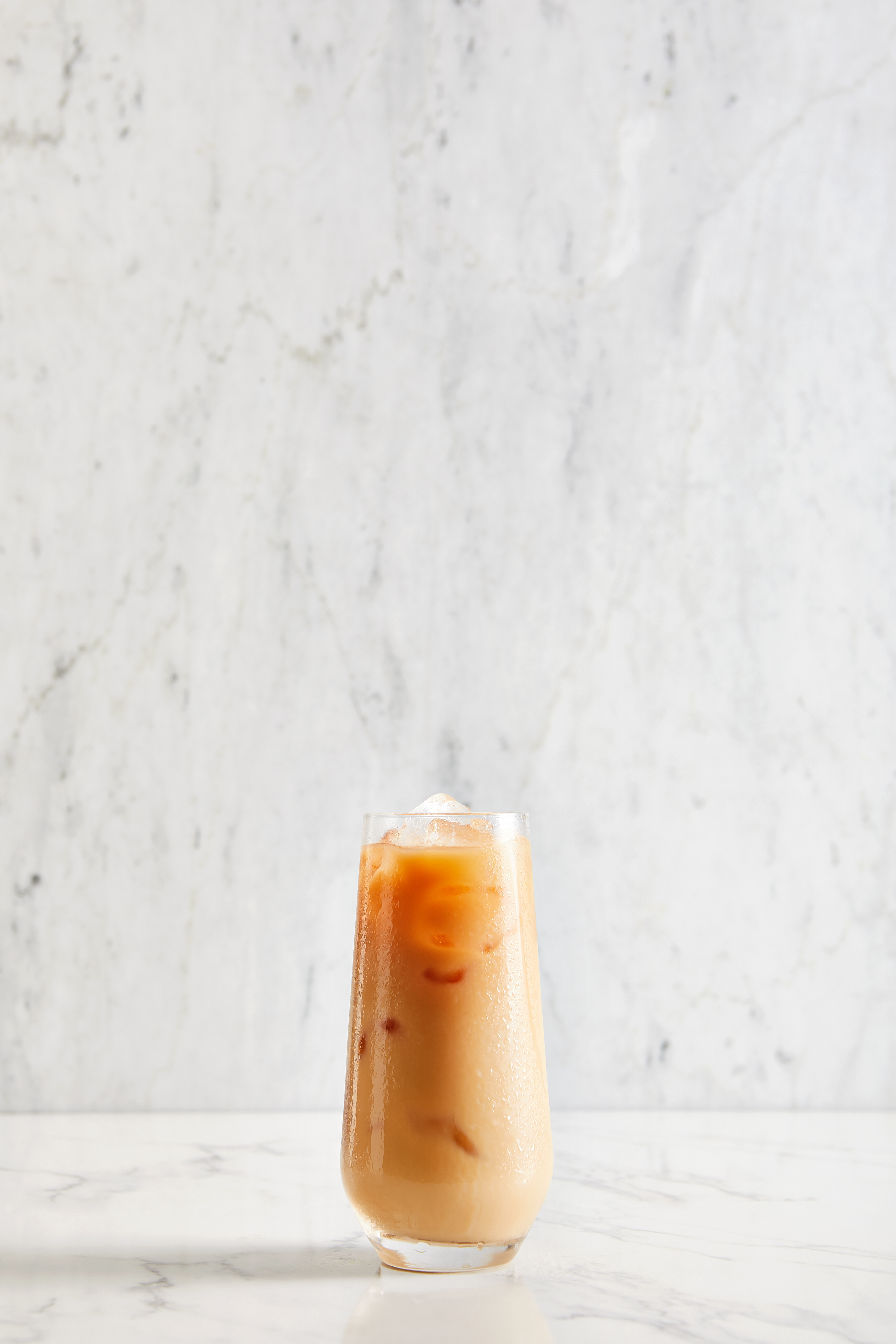 A refreshing iced coffee served in a glass, placed elegantly on a polished marble counter