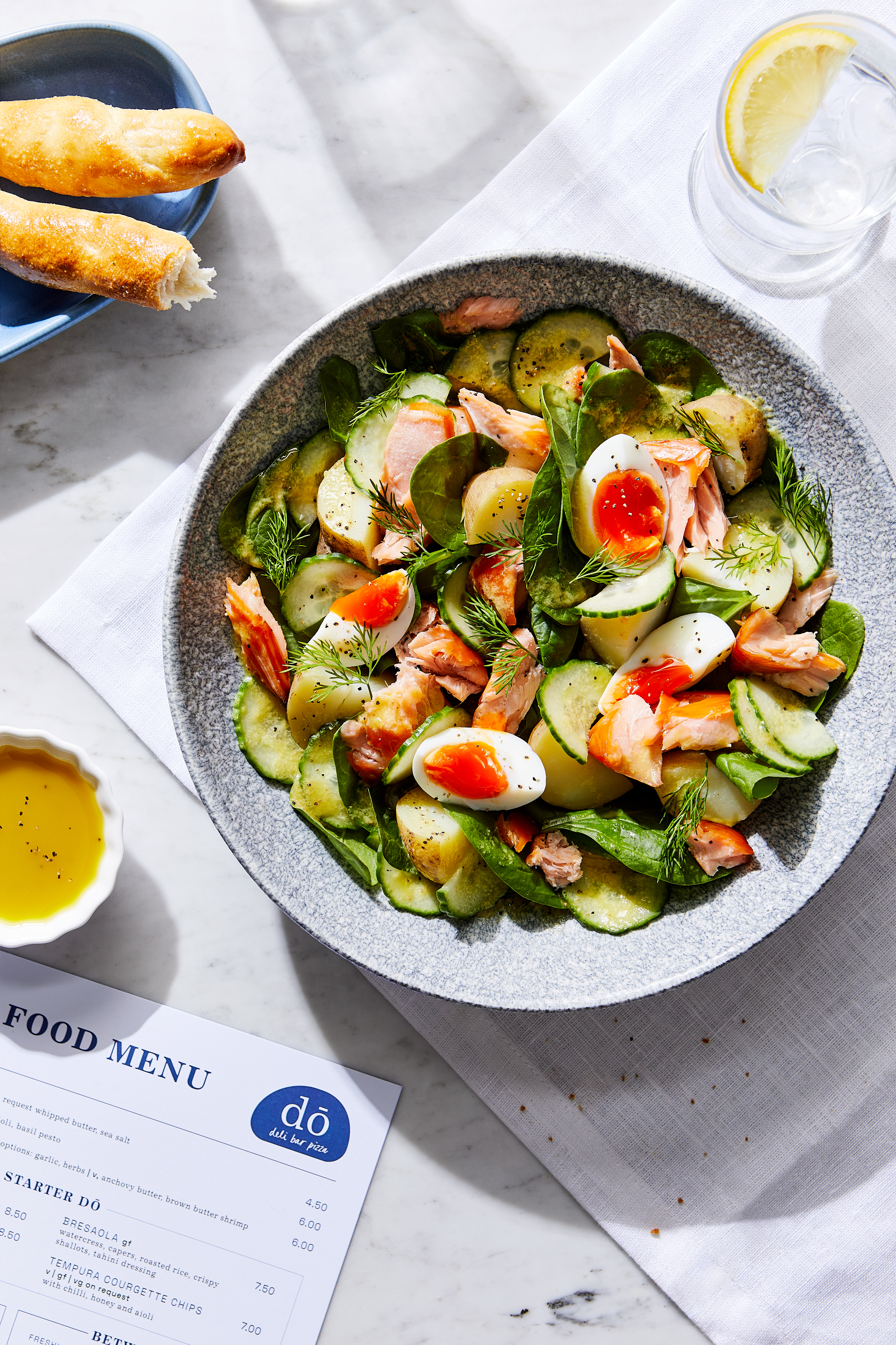 A bowl of fresh salad featuring bread, cucumber, and various colorful ingredients arranged attractively