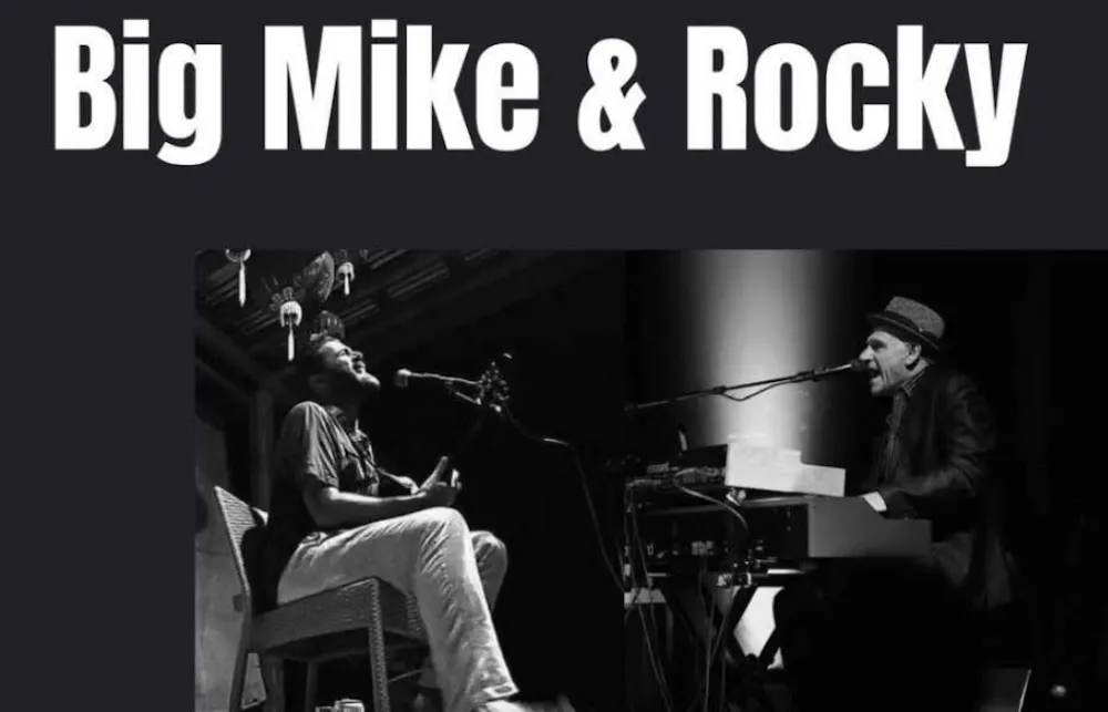 a man sitting in a chair with a microphone and a man playing piano