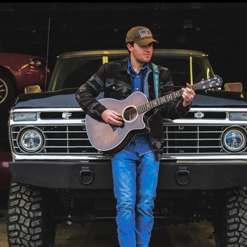 a man holding a guitar in front of a truck