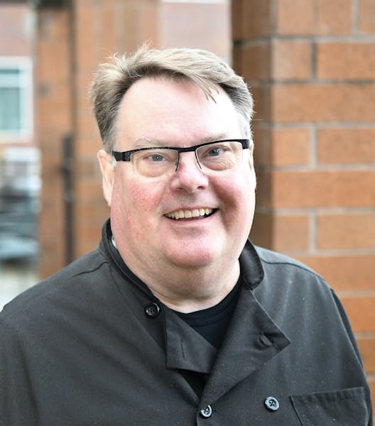 a man wearing glasses and smiling at the camera