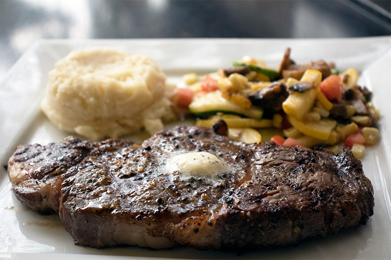 Sports restaurant near Malibu, California serving plate of steak, mashed potatoes and sautéed vegetables.