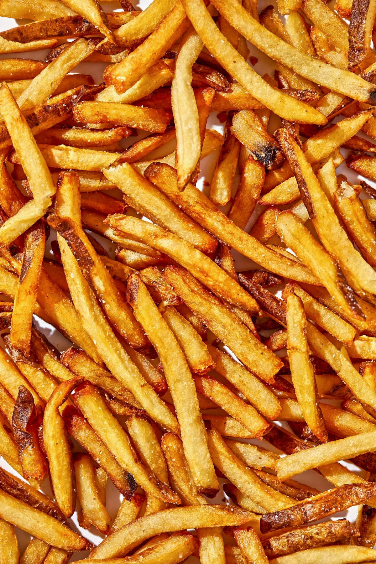 a hot dog on a bun next to a pile of fries