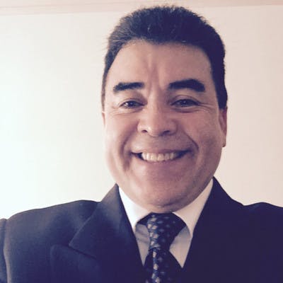 a man wearing a suit and tie smiling at the camera