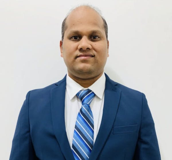 a man wearing a suit and tie smiling at the camera