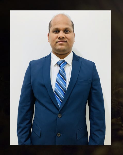 a man wearing a suit and tie smiling at the camera