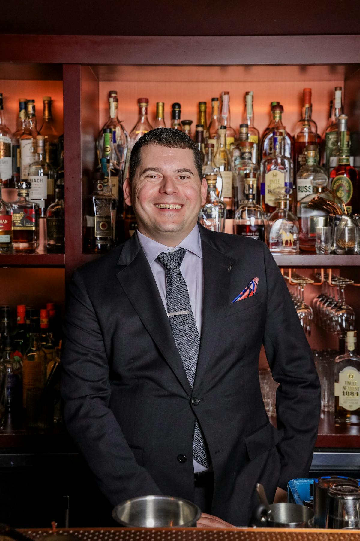 a man wearing a suit and tie holding a glass of wine
