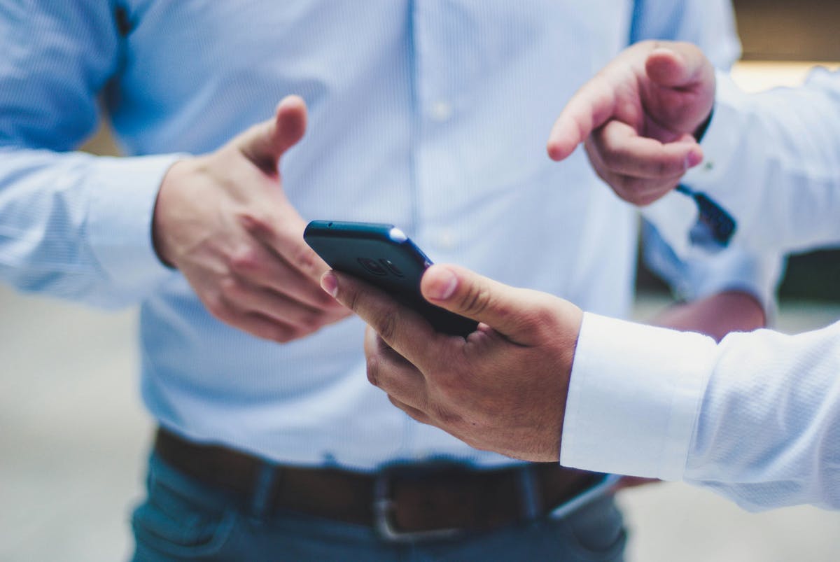 an iamge of a man showing his phone to a coworker