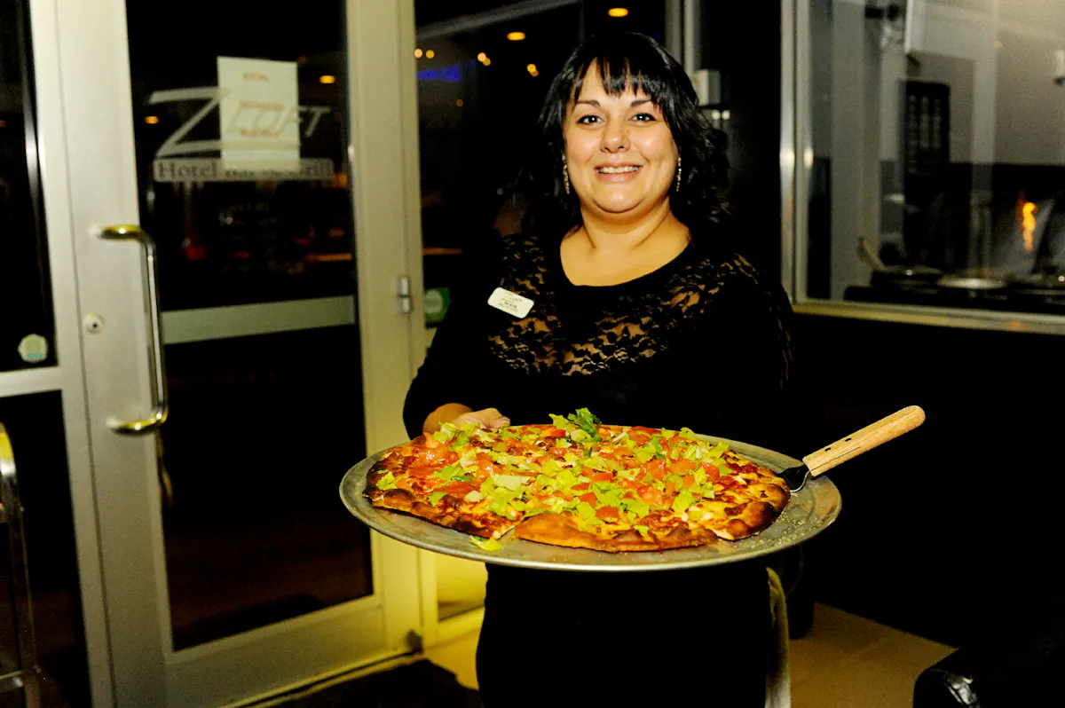 a woman standing in front of a pizza
