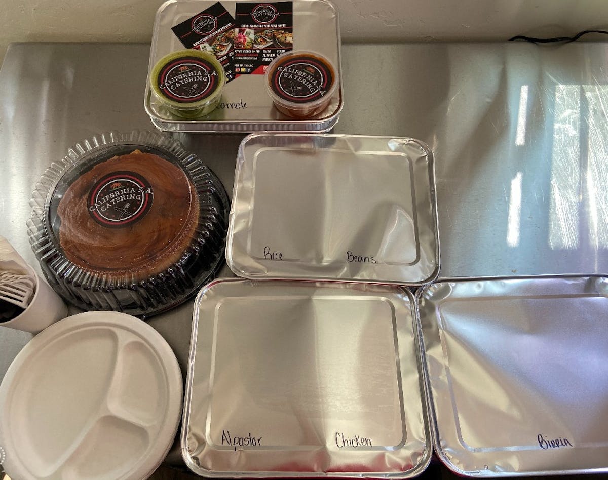 Three containers covered with plastic plates and two salsas