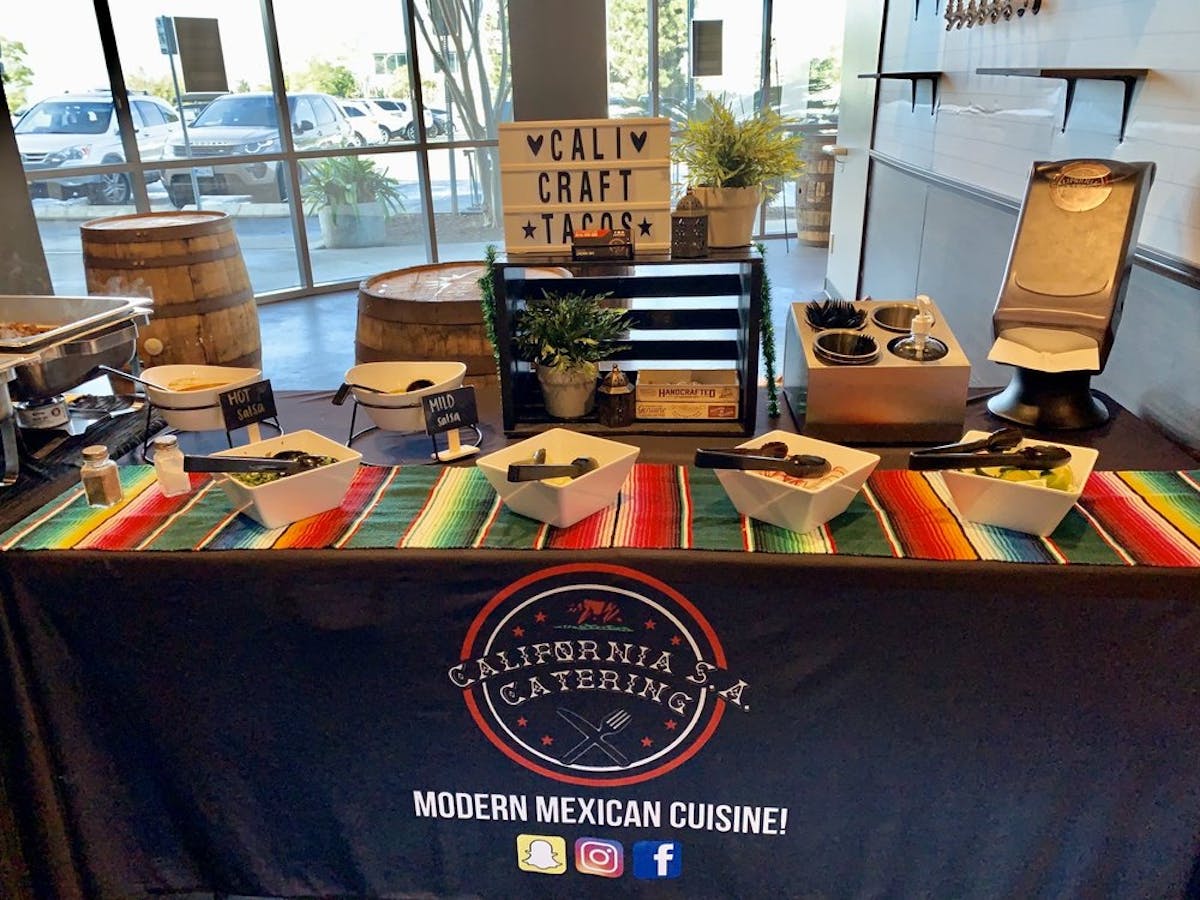 a photo of the table setup with condiments with a Cali Craft tacos sign