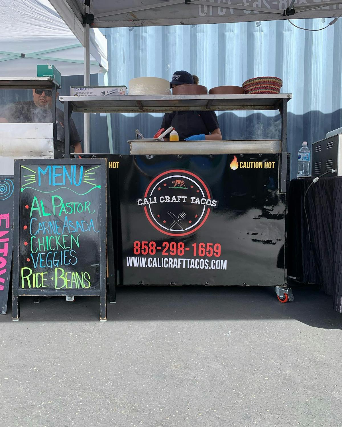 A grill on wheels with the Cali Craft Tacos logo with a menu board in front