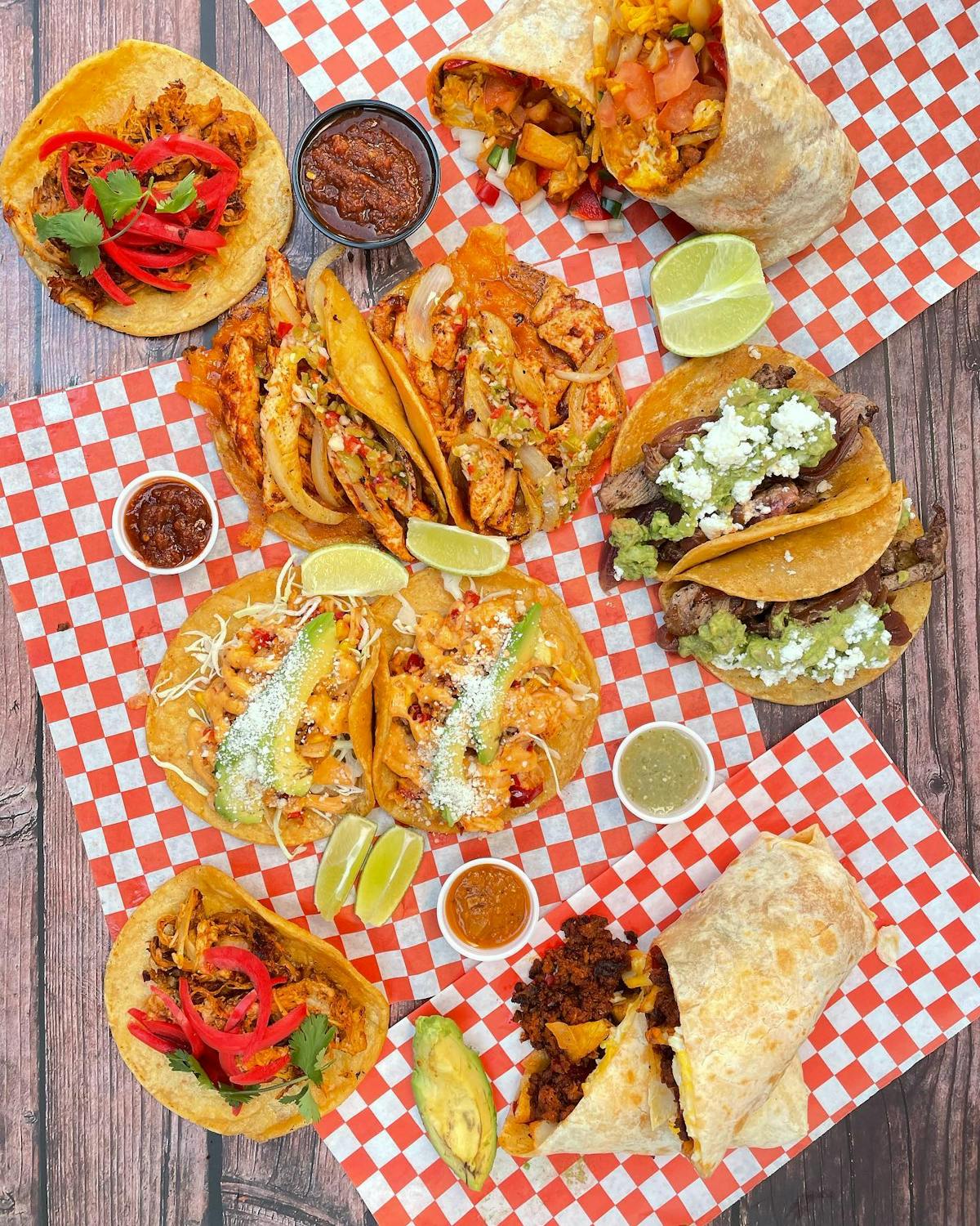 a photo of different foods that includes tacos, burritos with salsas and slices of lime