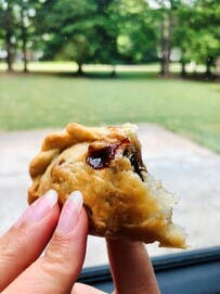 a hand holding a half eaten donut