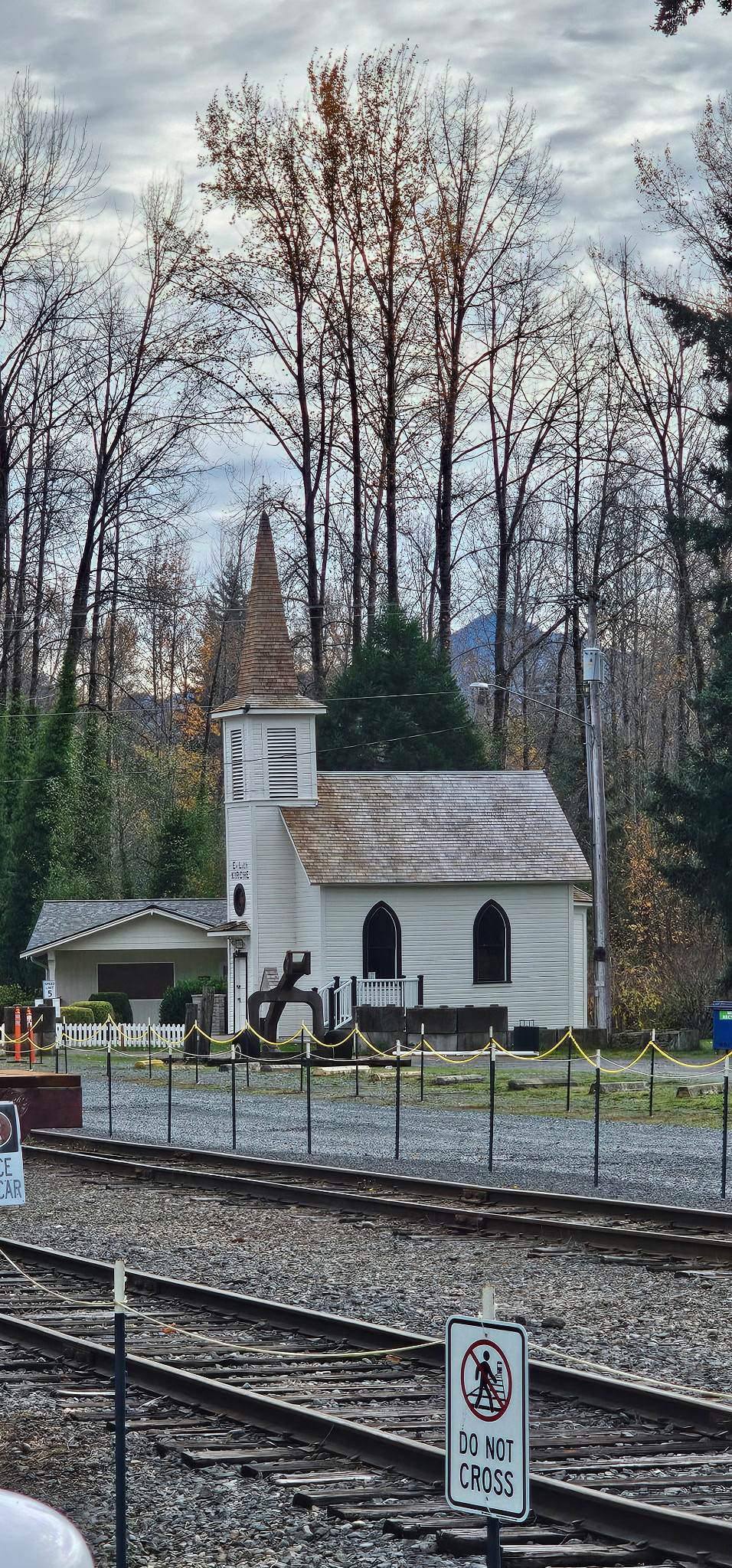 a white church with a steeple and a fenced in road