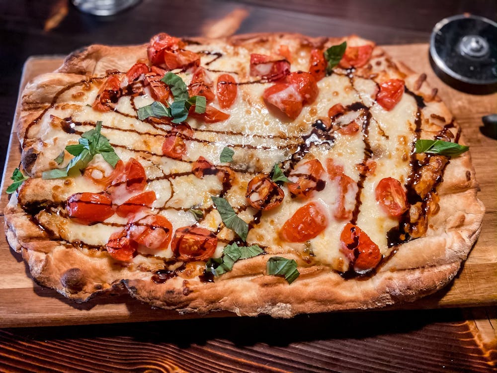 a pizza sitting on top of a wooden cutting board