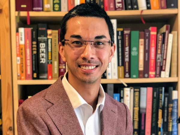 a man in a suit and tie in front of a book shelf