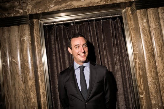 a man wearing a suit and tie standing in front of a window