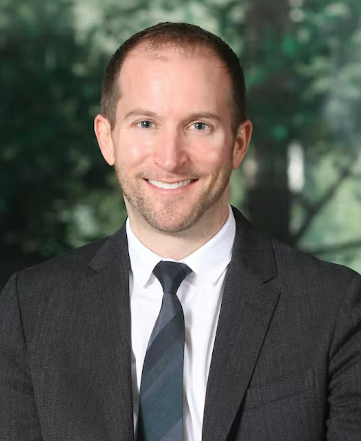 a man wearing a suit and tie smiling at the camera