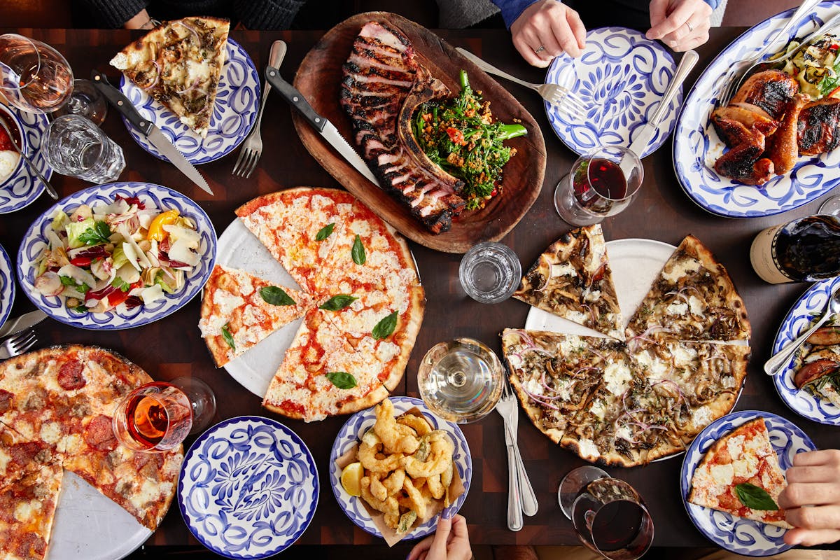 many different types of pizza and grilled mains on a table