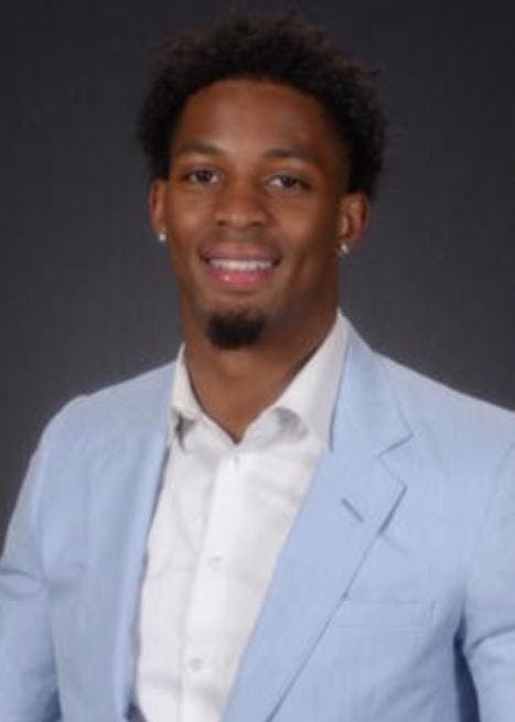 a man wearing a suit and tie smiling at the camera