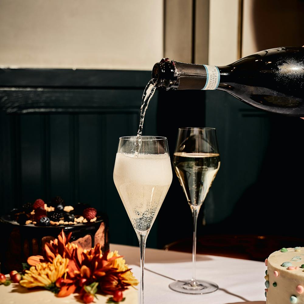 a cake sitting on top of a wooden table topped with glasses of wine