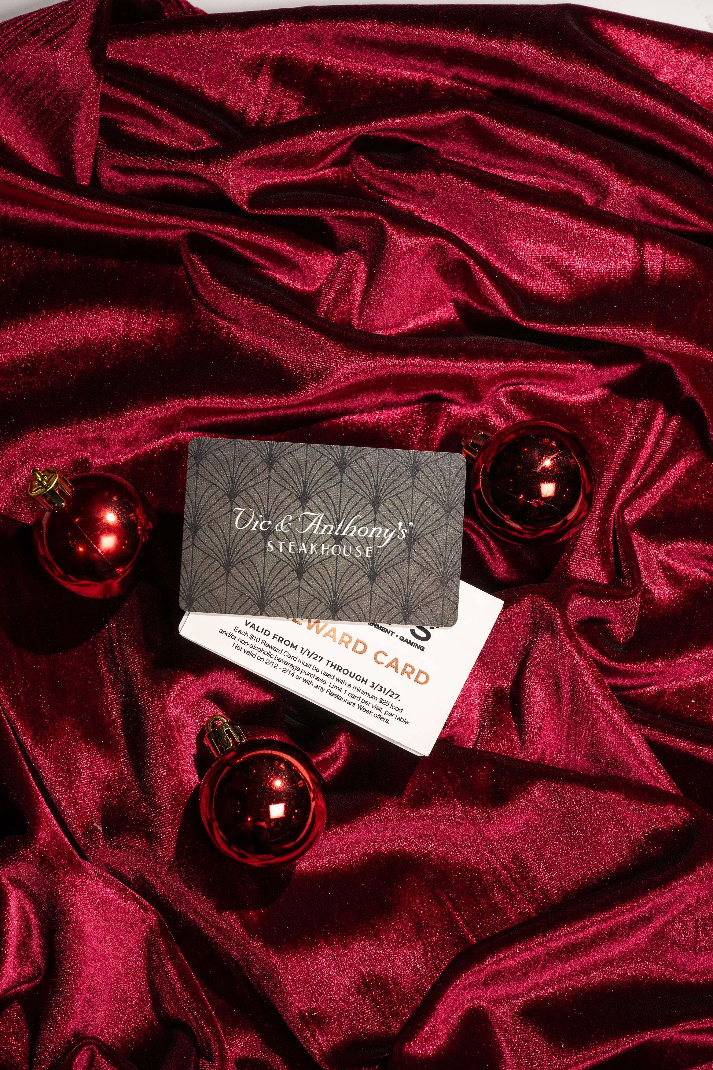 a card and ornaments on a red fabric