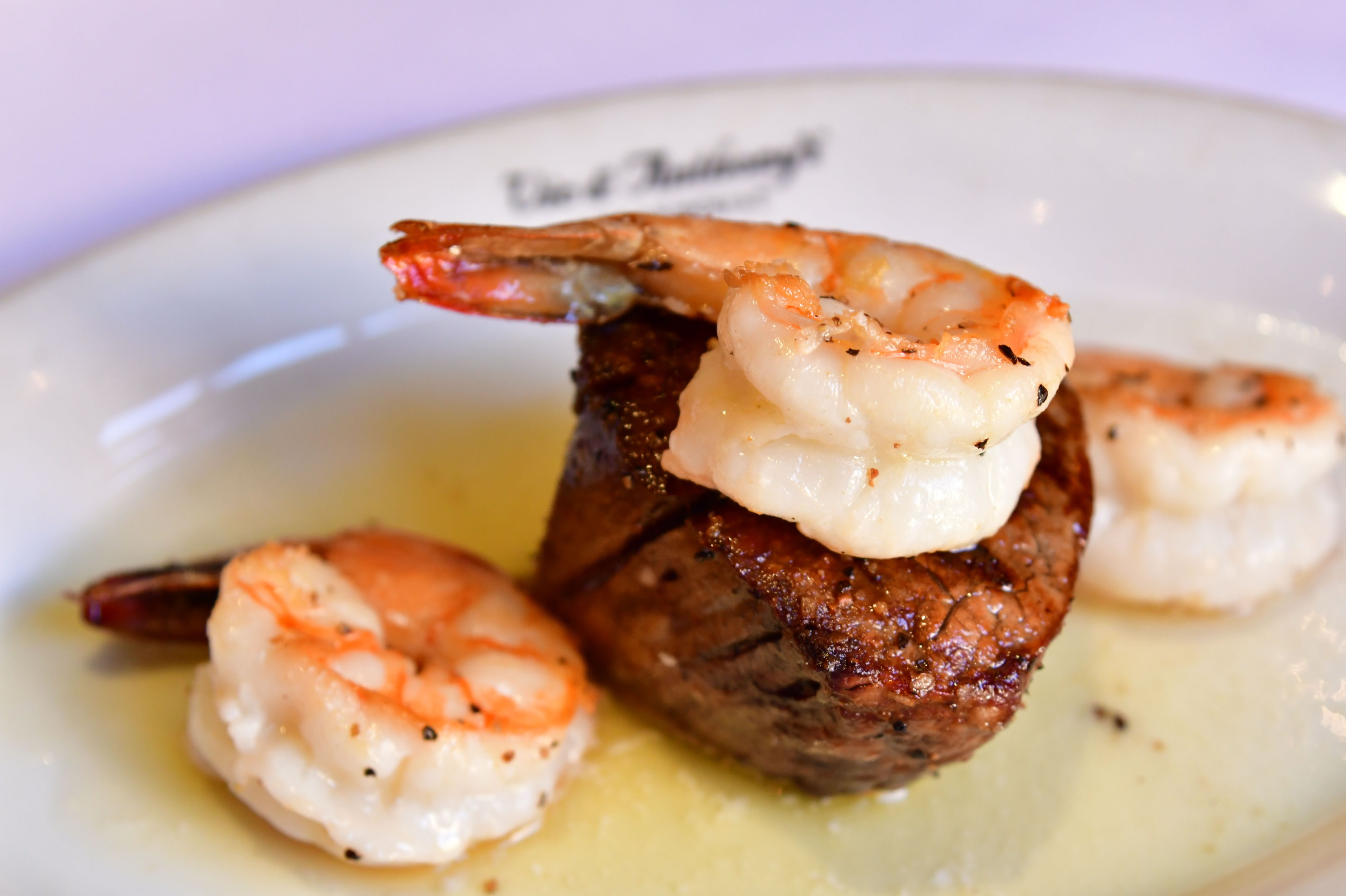 A juicy steak rests on a wooden cutting board beside two elegant wine glasses
