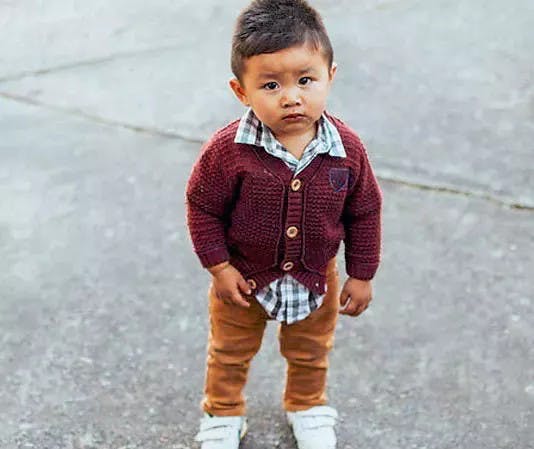 a little boy standing in a parking lot