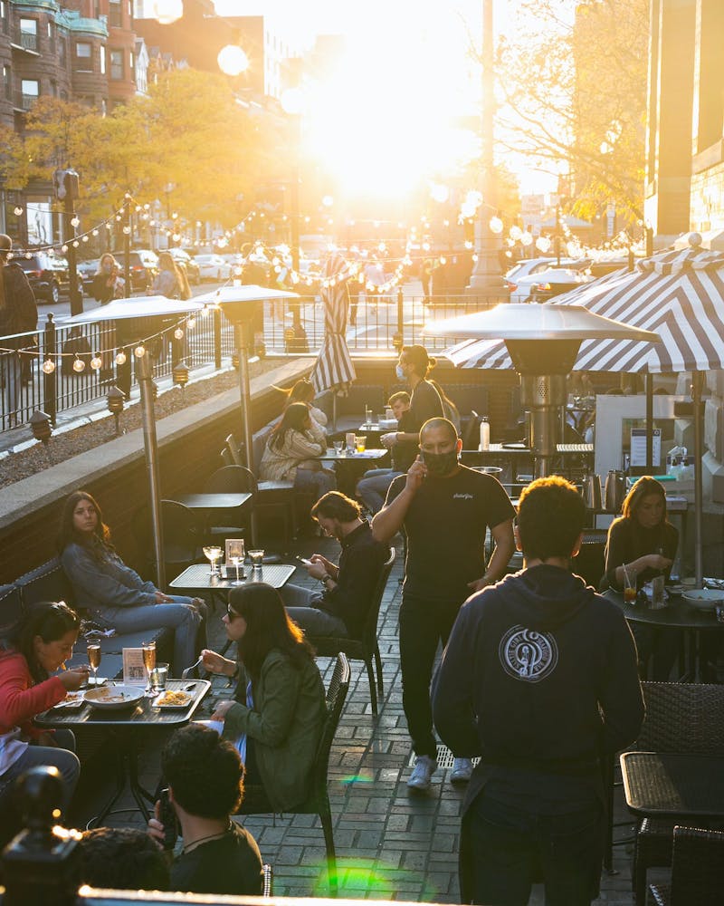 Shot of Saltie Girl Boston's exterior street patio with people dining in late fall afternoon during golden hour