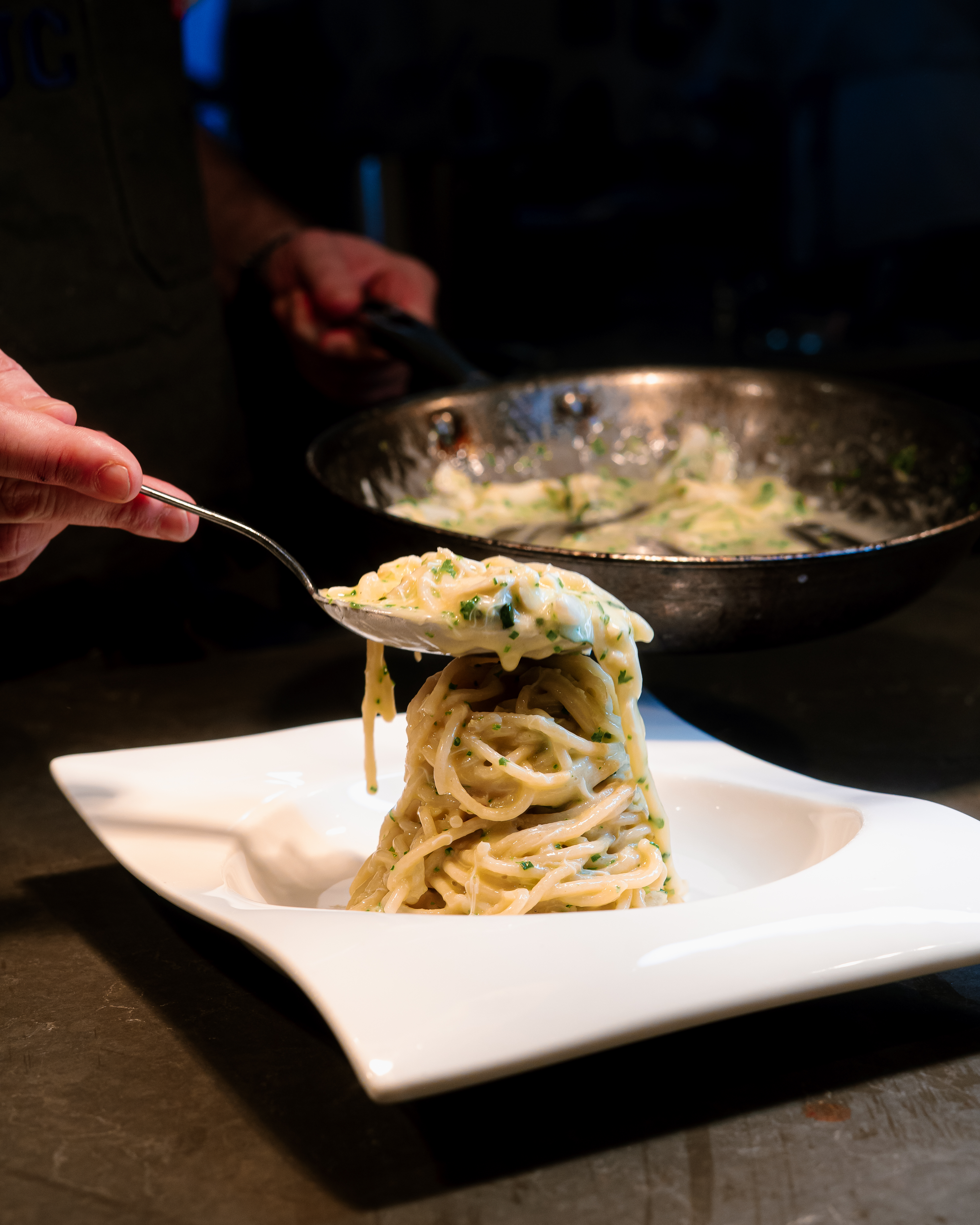 a person holding a spoon over a plate of spaghetti