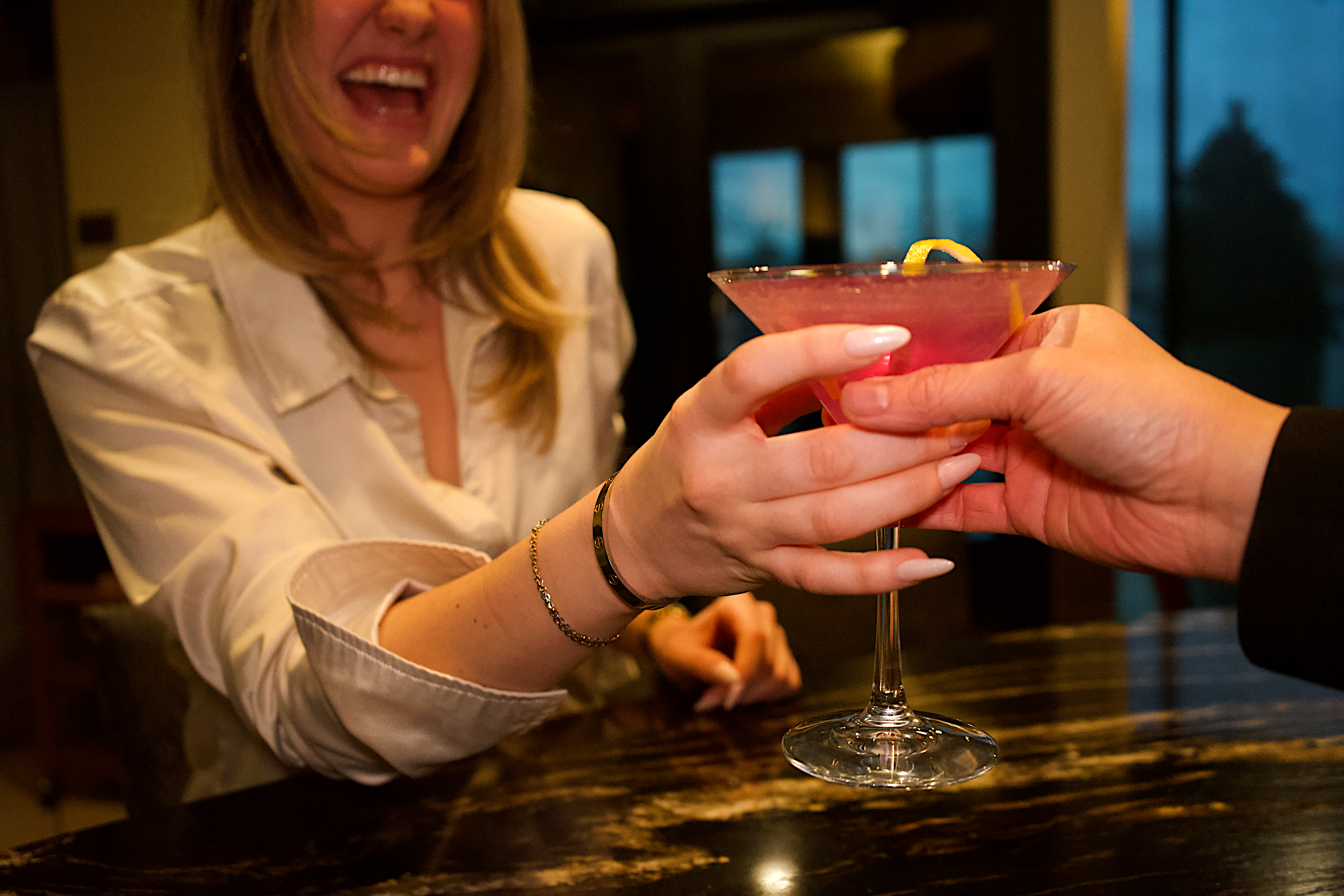 a woman holding a glass of pink liquid