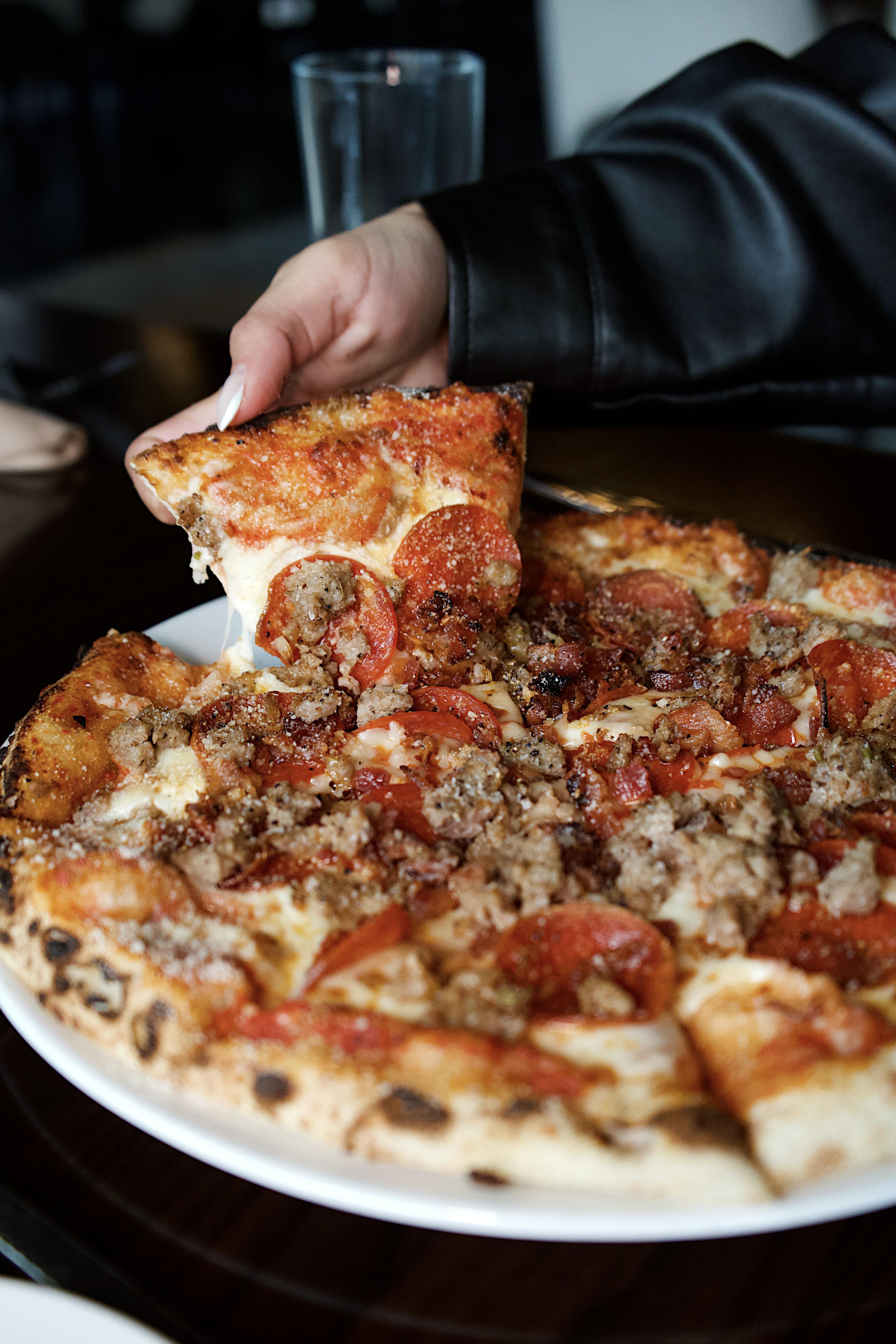 a person taking a slice of pizza