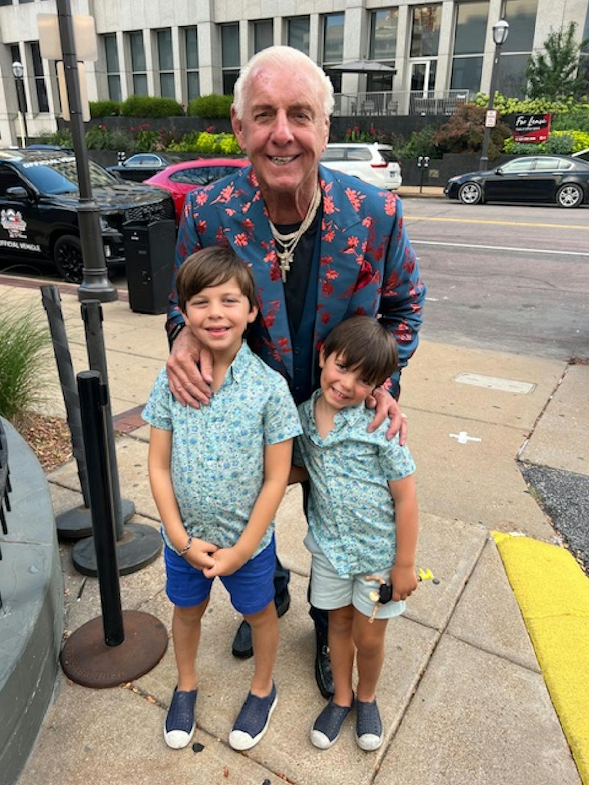 Ric Flair and a little boy standing on a sidewalk