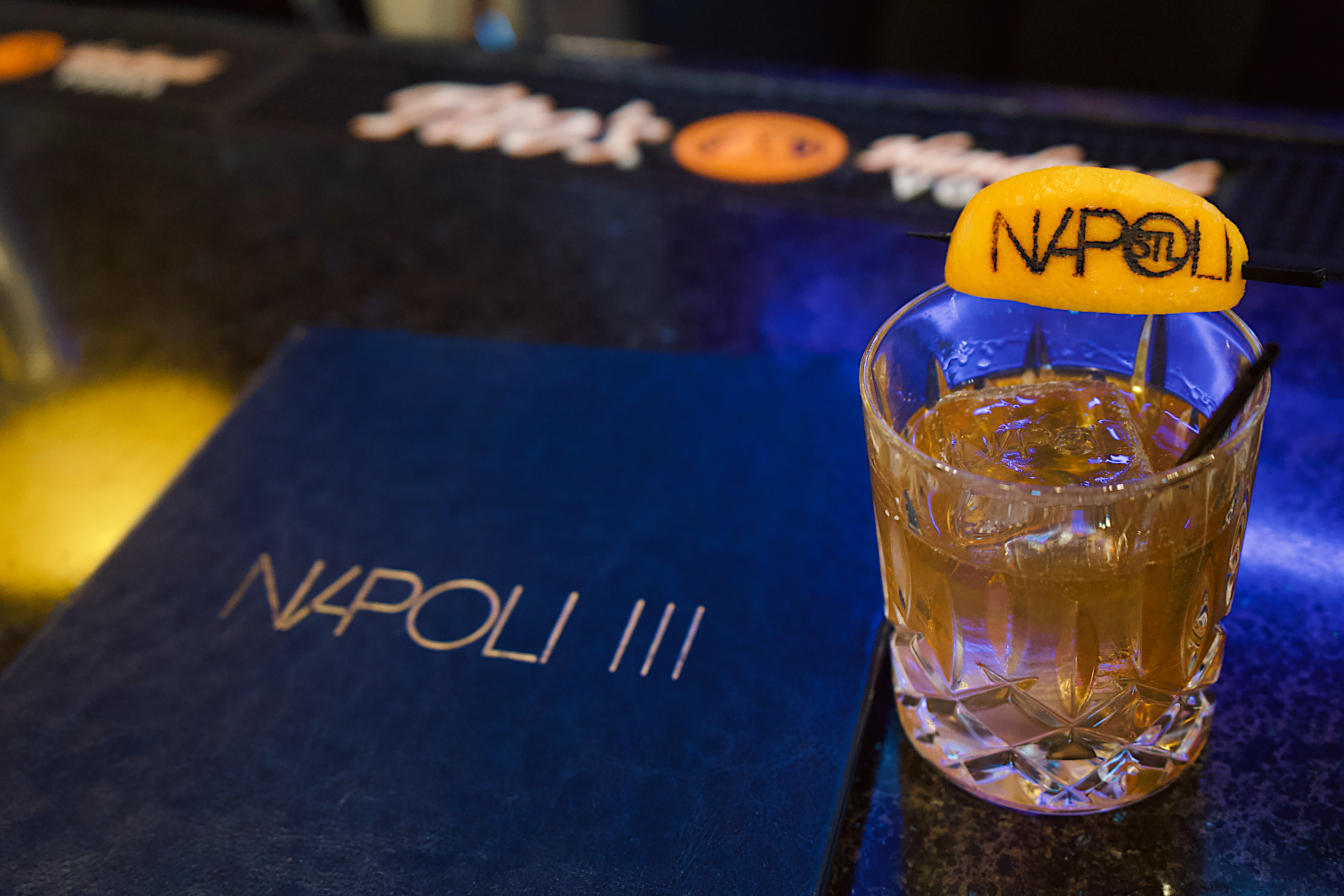 a glass of liquid with a slice of orange on top of it