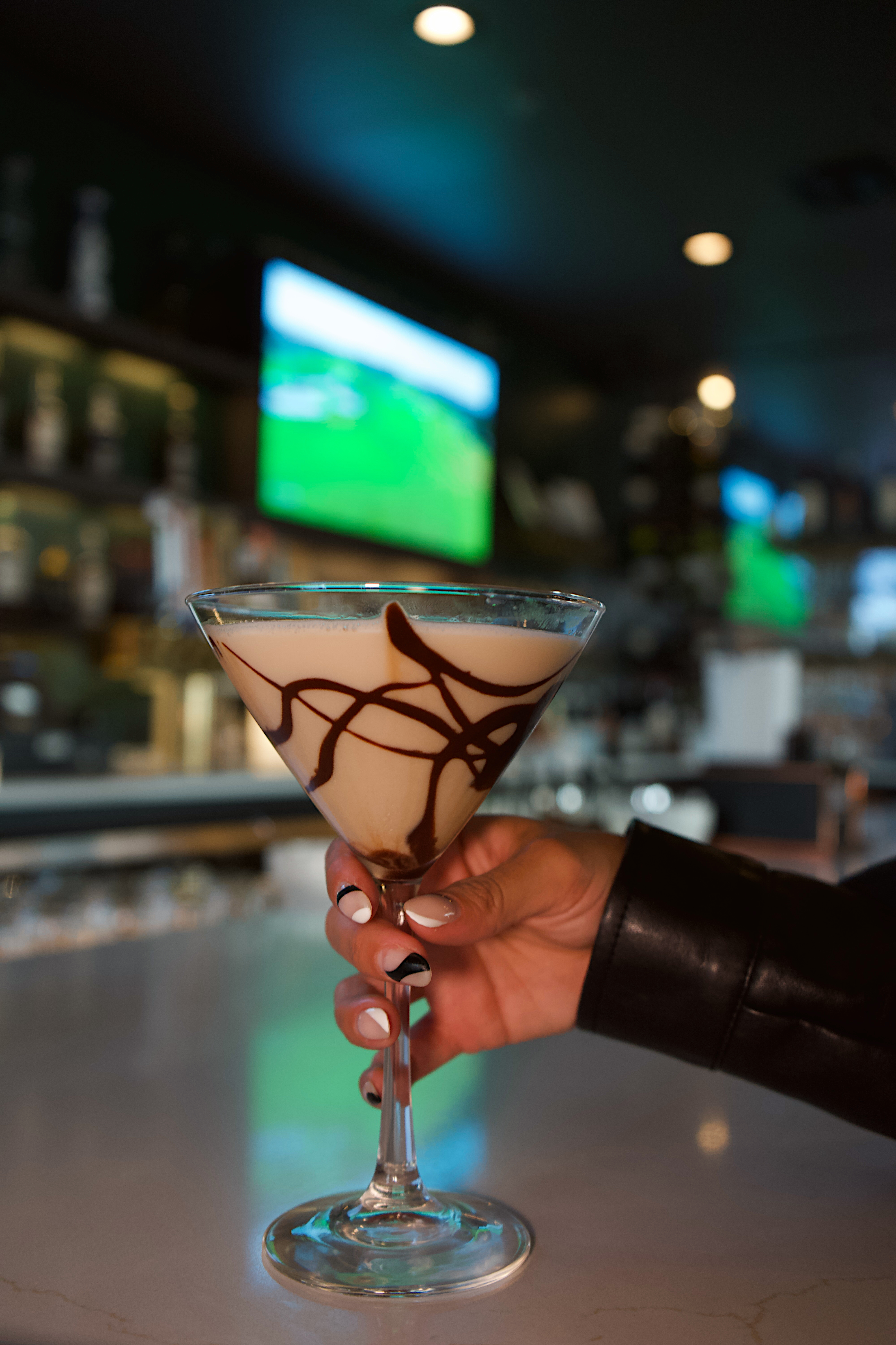 a hand holding a glass of liquid