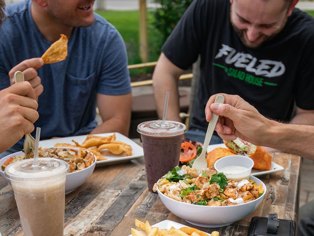 Friends laughing and eating salad house food at picnic table