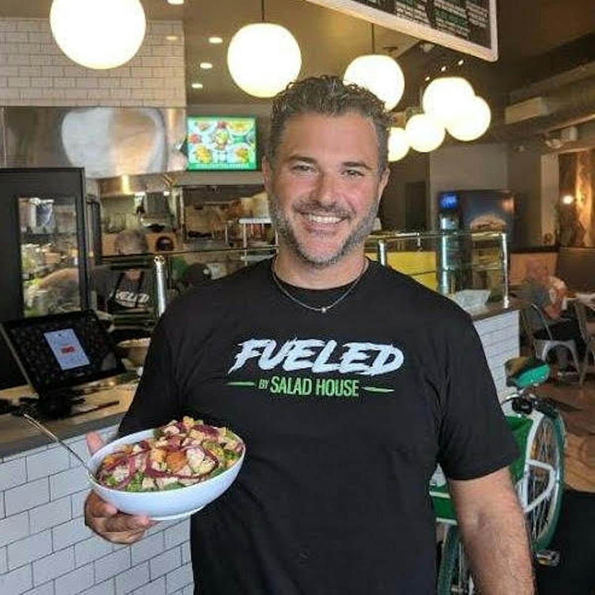 a man holding a pizza in a restaurant