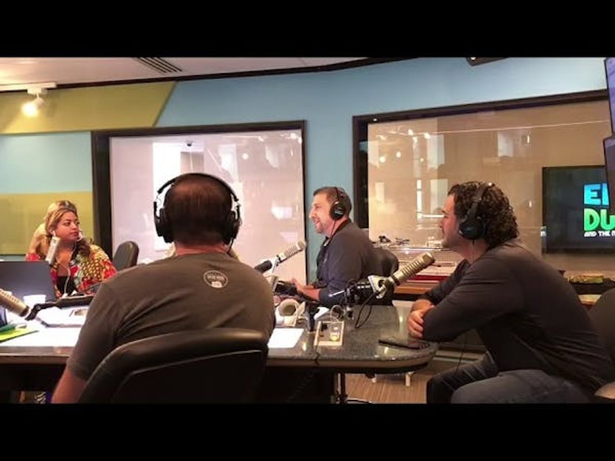 a group of people sitting at a table looking at a laptop