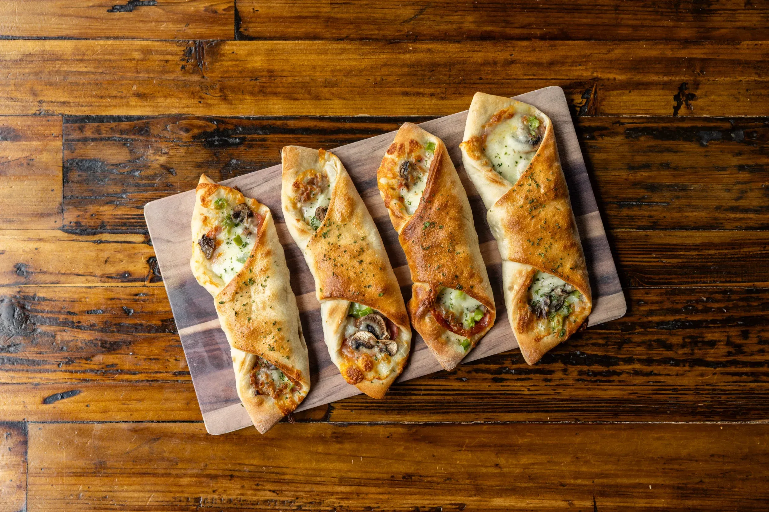 a group of pizzas on a wooden board
