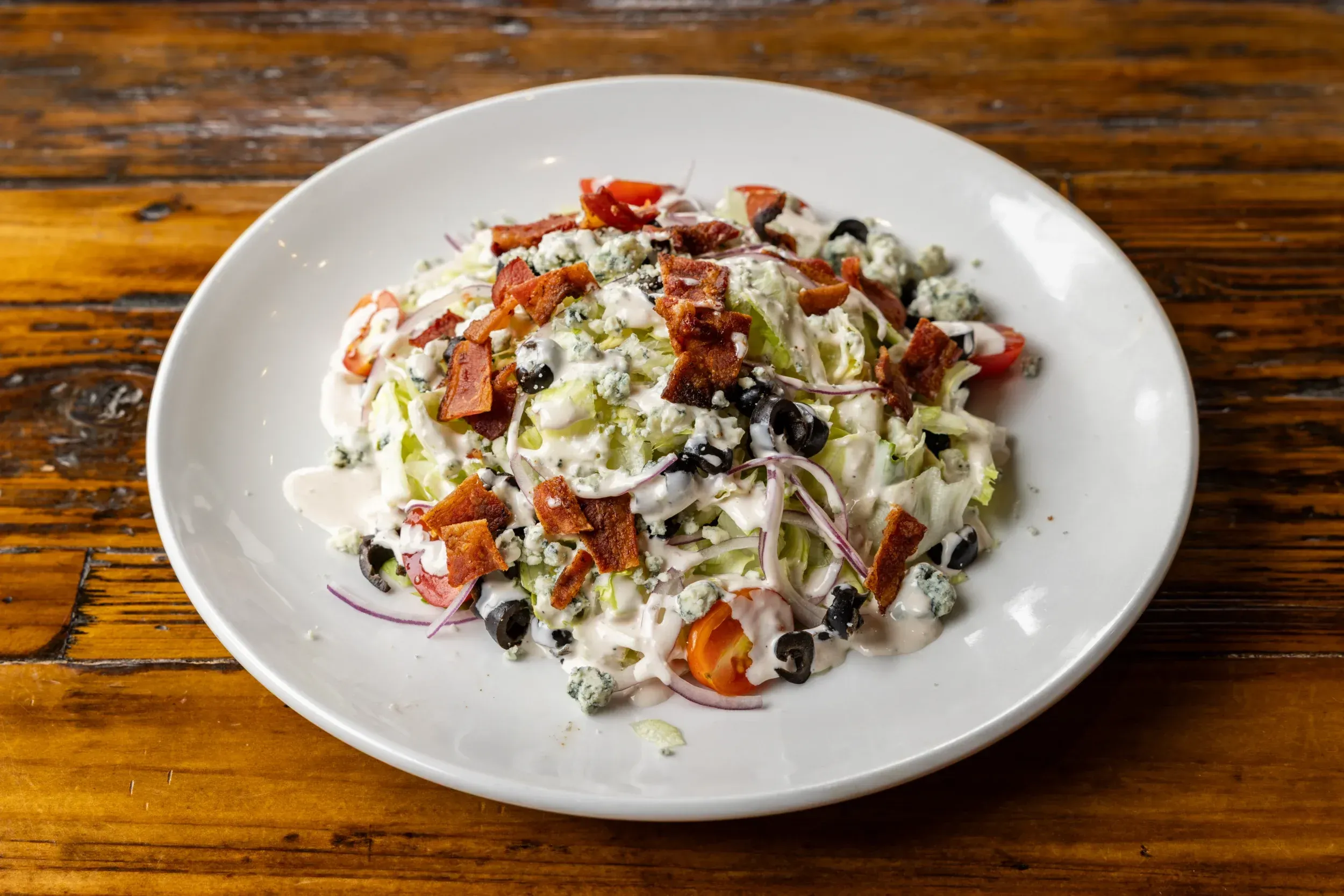 a plate of salad with bacon and olives