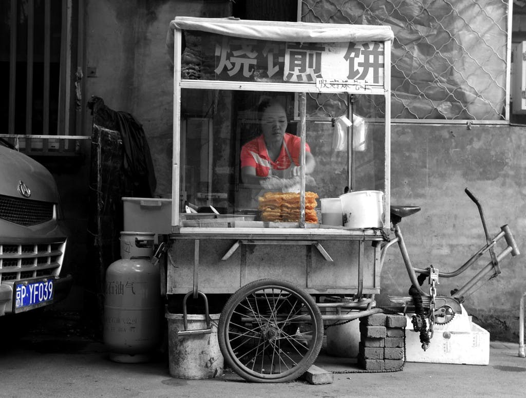a food stand with a woman standing behind it cooking food