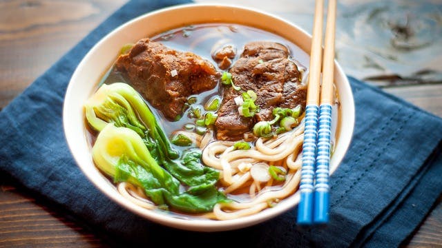 a bowl filled with ramen, vegetables and meat topped with chopsticks