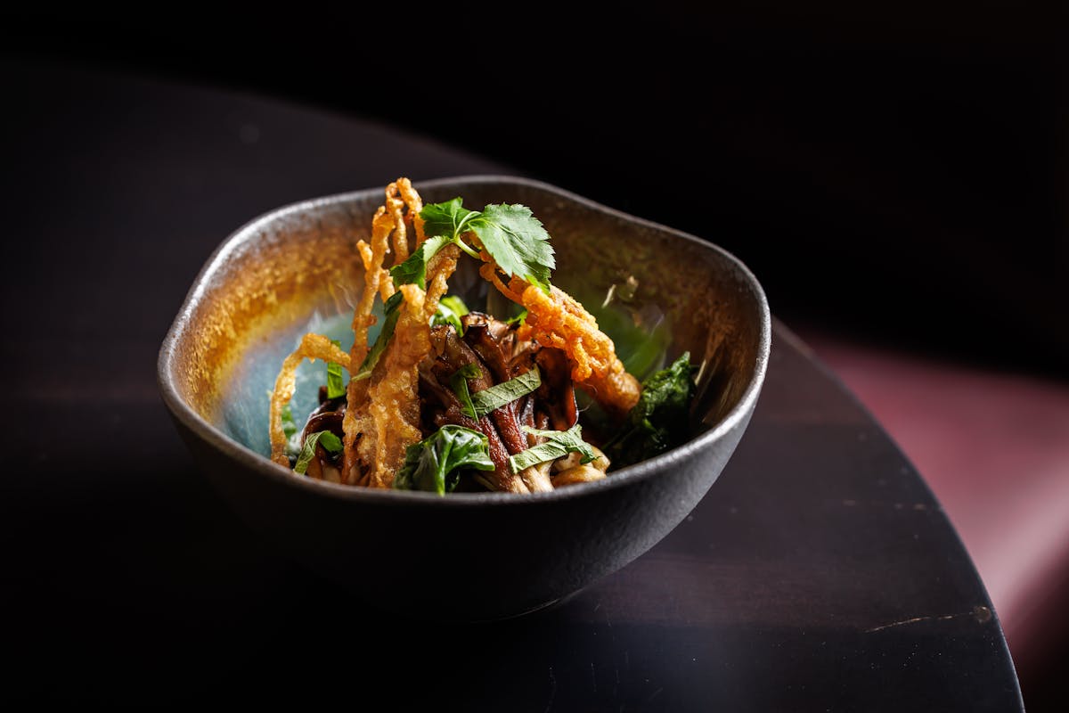 A bowl of food placed on a wooden table, showcasing a colorful meal ready to be served