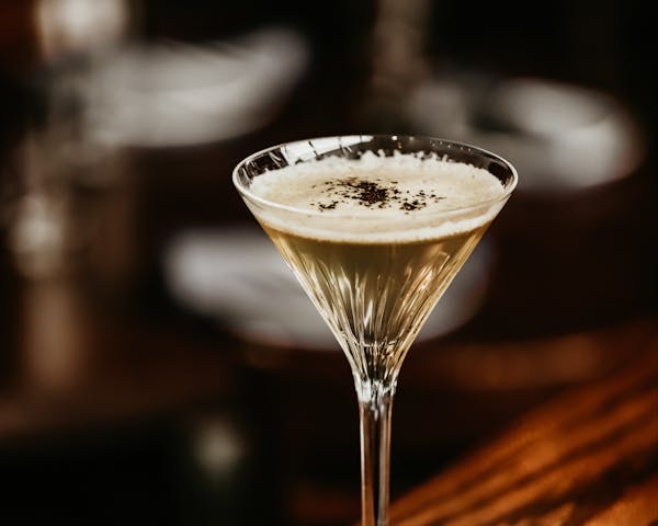 a glass of a cocktail sitting on top of a table