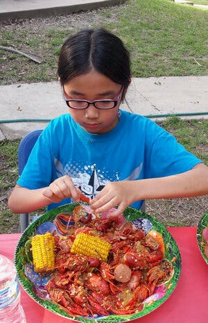 a little boy sitting at a table with a plate of food
