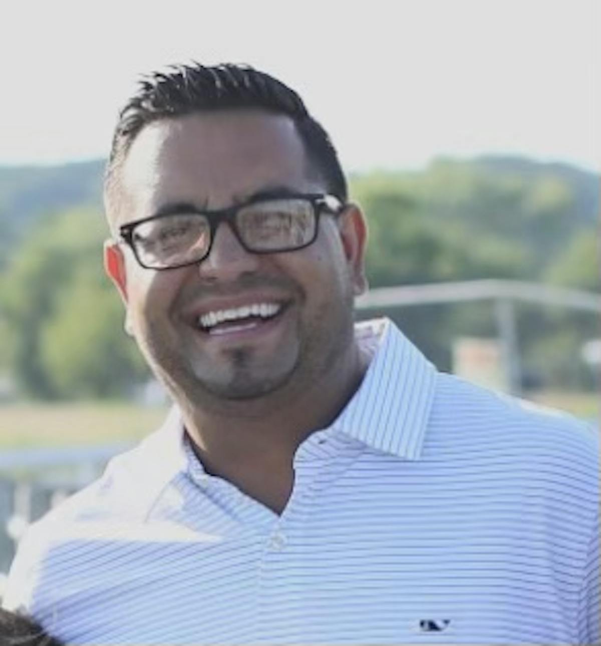 a man wearing glasses and smiling at the camera