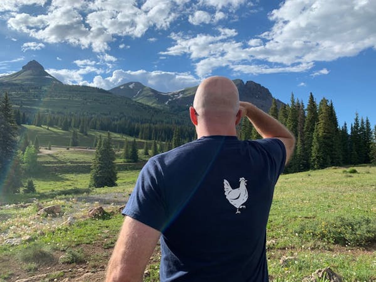 a man standing in a field with a mountain in the background